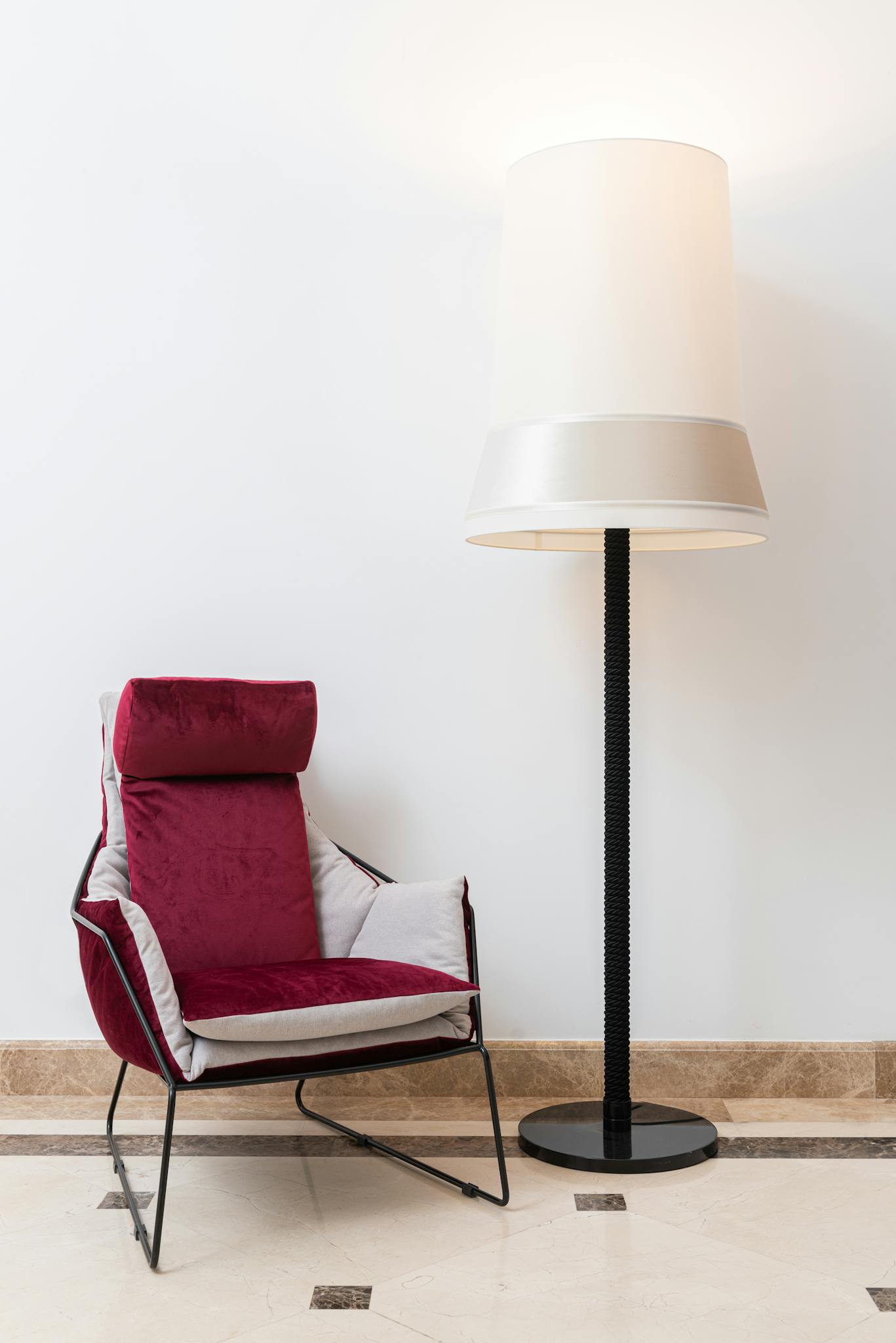 A stylish armchair and lamp set against a minimalist interior design backdrop.